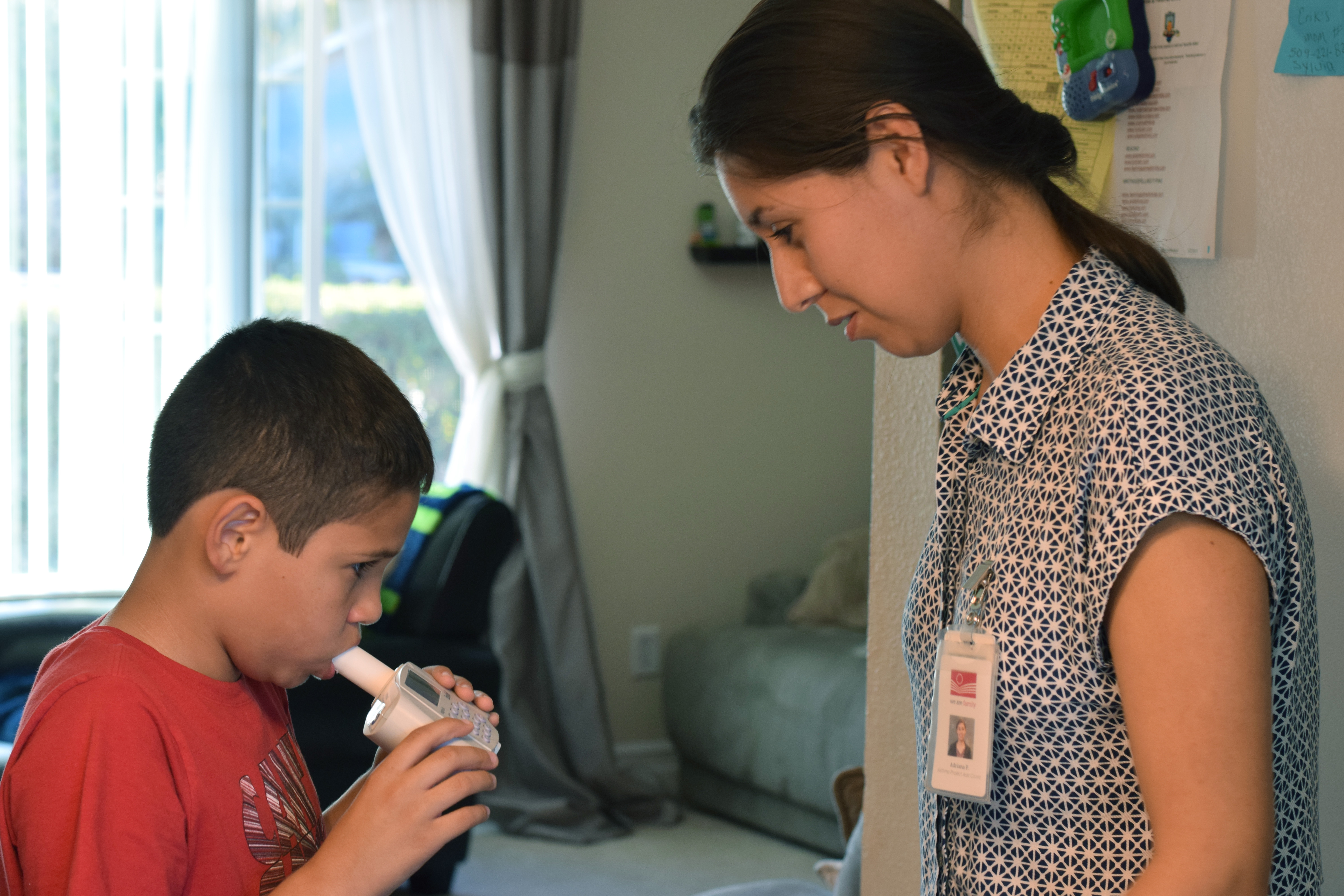 Adriana Perez of Yakima Valley Farmworkers Clinic uses a spirometer with a study participant to measure lung function during a home visit.