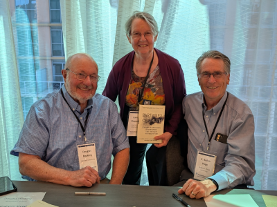 Lianne Sheppard holds the book "Particles of Truth" with authors Douglas Dockery and C. Arden Pope.