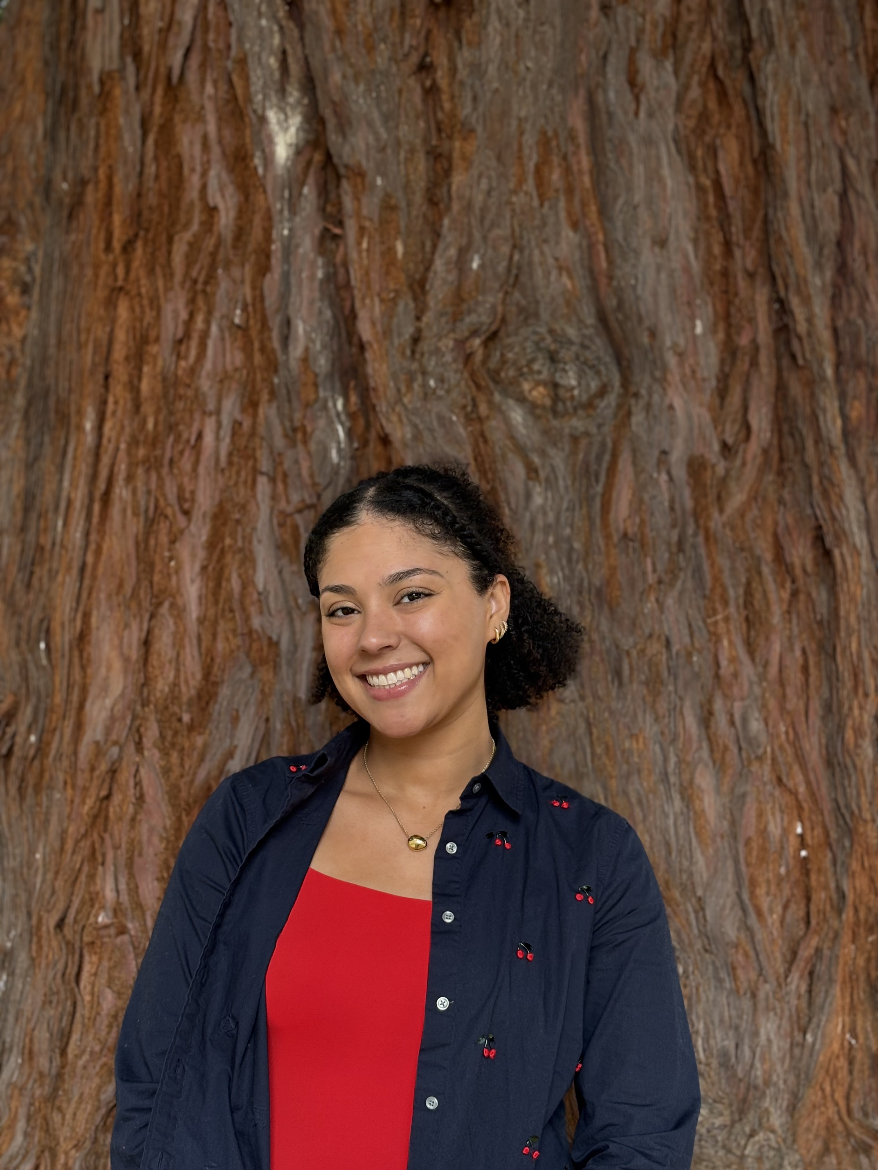 Elizabeth Blake smiles in front of a tree trunk.