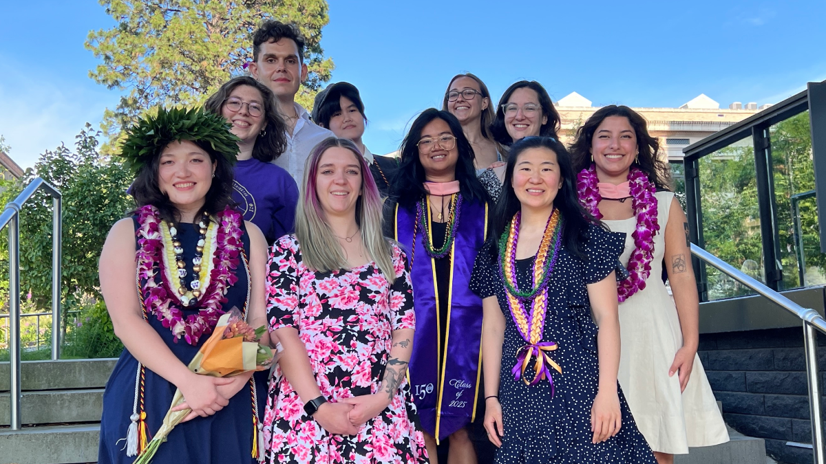 Ten students stand on steps on the UW campus in a group. Two on either end are wearing leis.