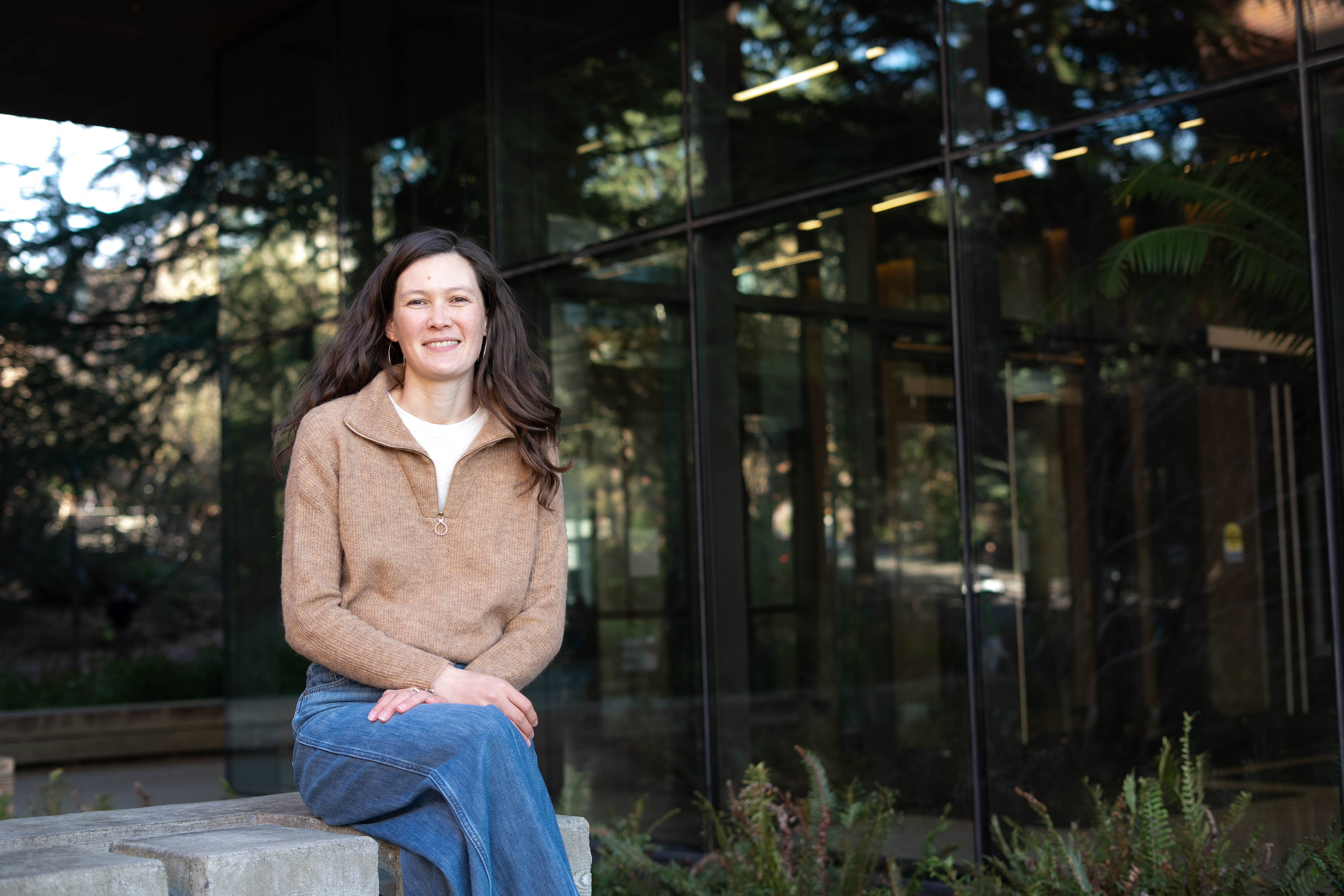 Marissa Childs sits outside in front of a glass building on the UW campus.
