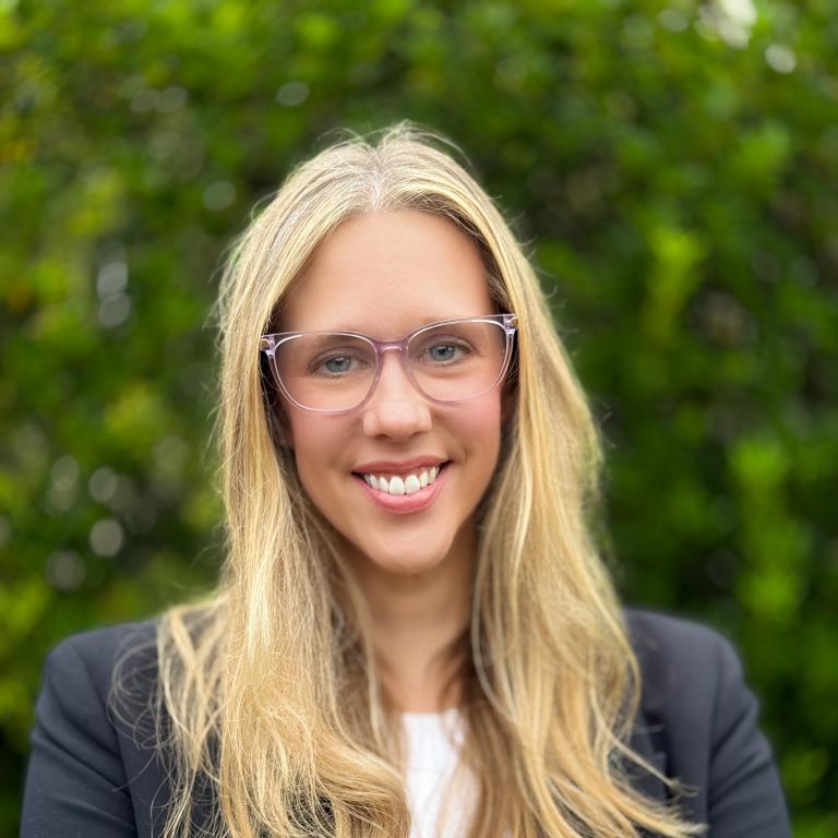 Lady with blonde hair and clear glasses smiling