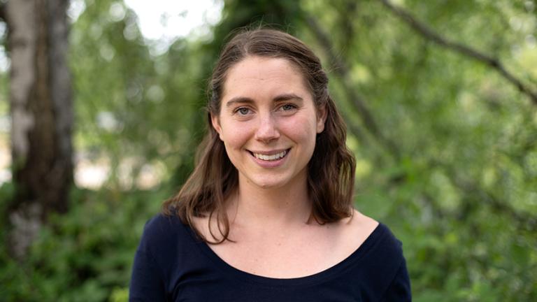 Headshot of Claire Pendergrast standing in front of a blurry leafy background.  Photo: Elizar Mercado