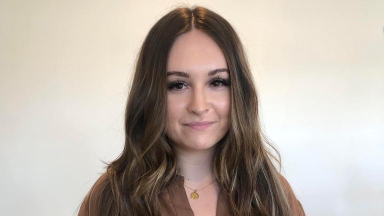 Portrait of Inna Antonchuk looking at camera, wearing a gold pendant necklace with the letter V.