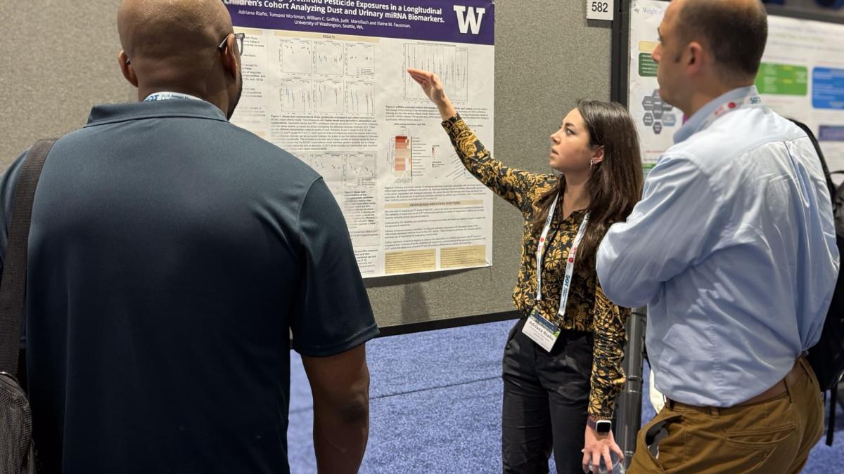 Adriana Riaño points to her research poster while two people look on.