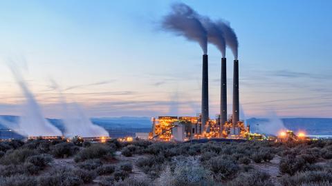 Smoke rises from three smokestacks at a power plant.