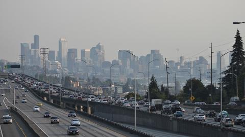 Photo of downtown seattle and interstate 5 with heavy traffic. A haze of pollution obscures the buildings of downtown.