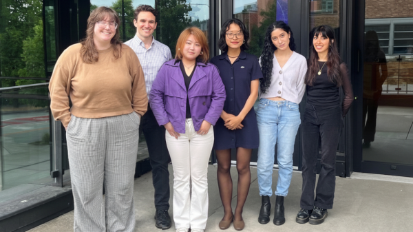 Six people including Hao stand in front of a campus building.