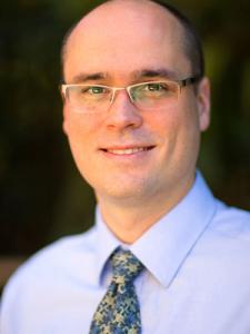 Dr Beck, a middle-aged bald white man with gold glasses in a nice shirt and tie