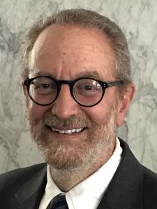 Howard Frumkin smiles at the camera, wearing glasses, a white shirt and dark jacket.