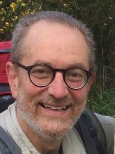 Howard Frumkin smiles wearing a backpack.
