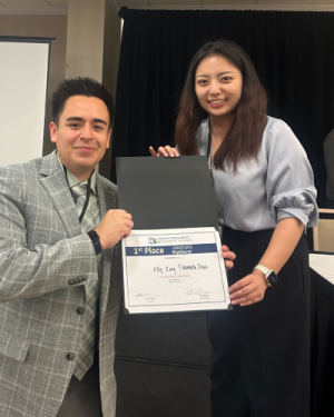 Leo Diaz and Ally Kong stand together in a conference room holding a certificate of their award reading 1st Place.