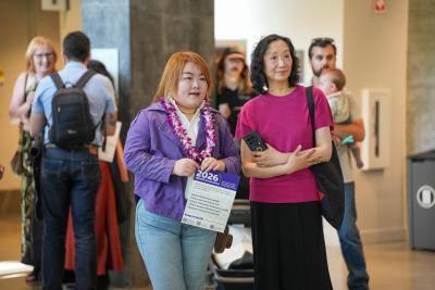 Xinyuan Hao stands with other people while holding a graduation program and wearing a lei.
