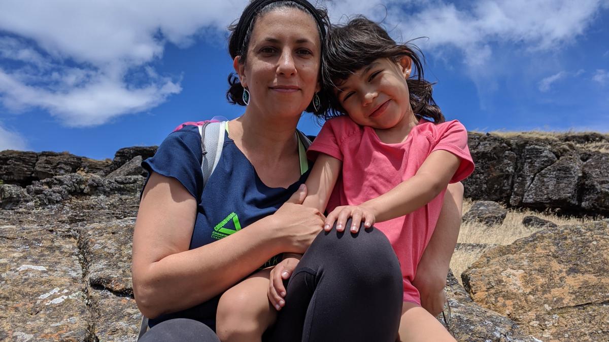 Cassie Cohen sits outside on a beautiful day with her daughter on her lap.